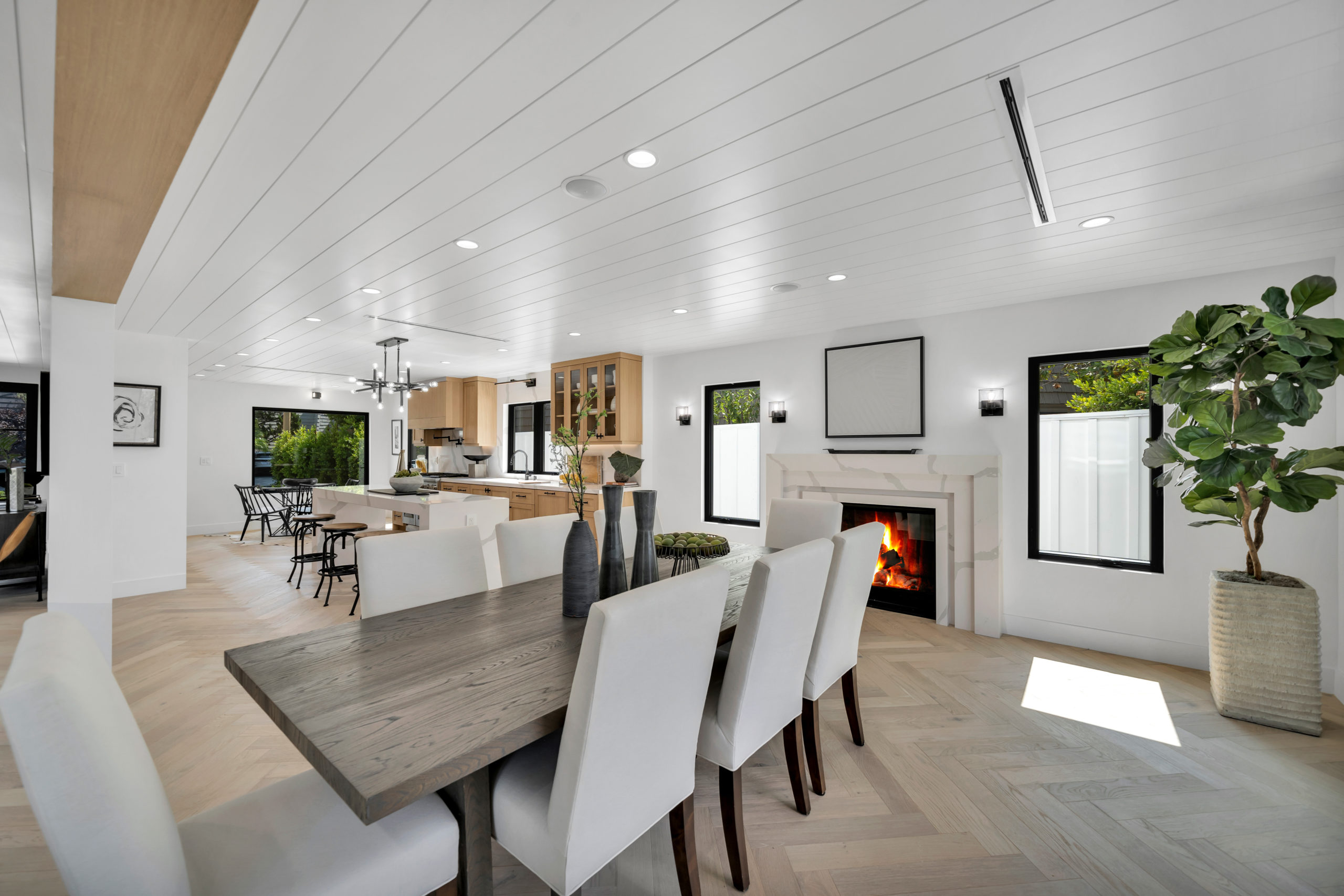 Open-plan kitchen and dining area with light hardwood flooring installed by Glamour Flooring