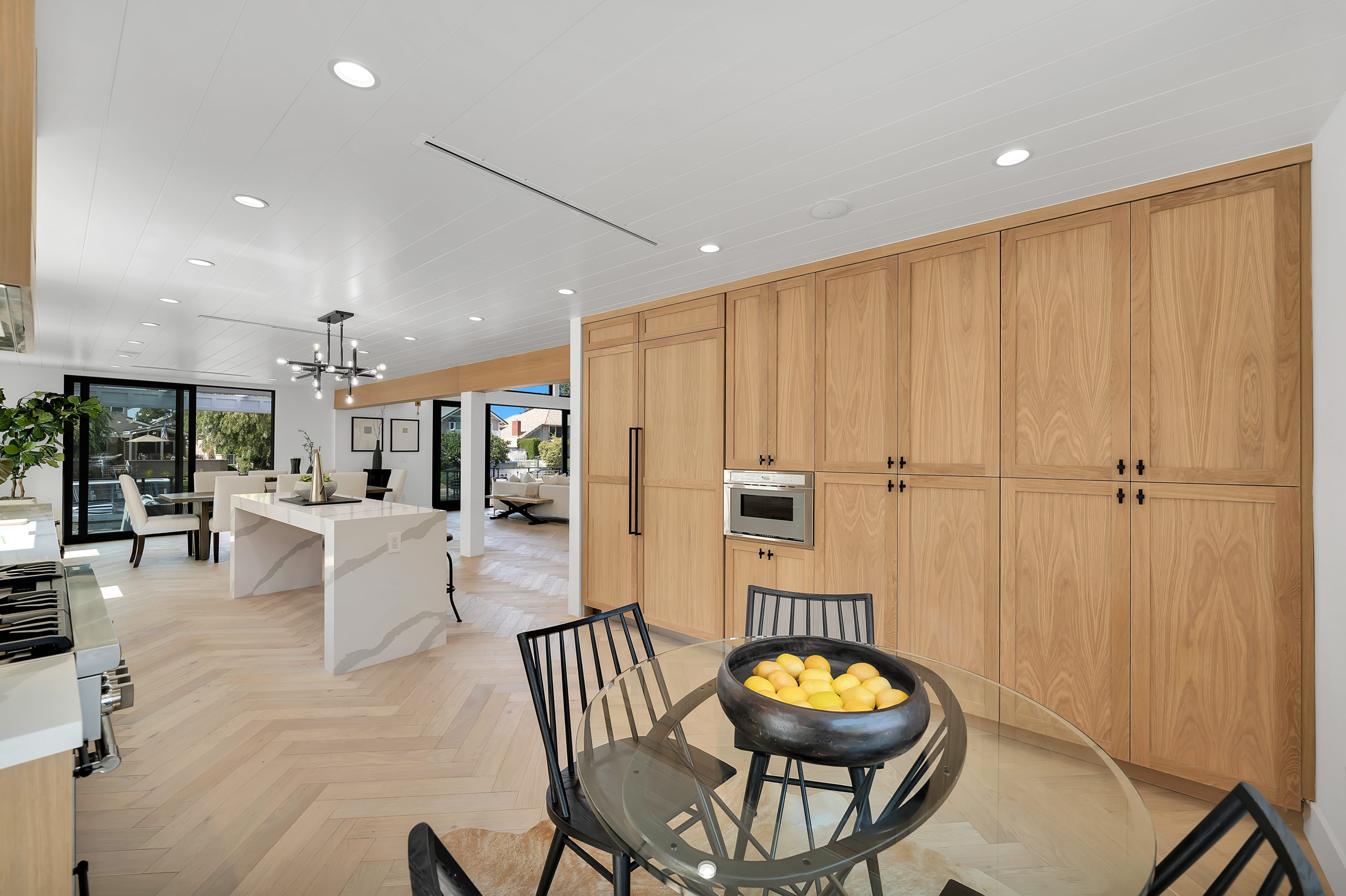 Light white oak herringbone flooring in an open kitchen and dining area