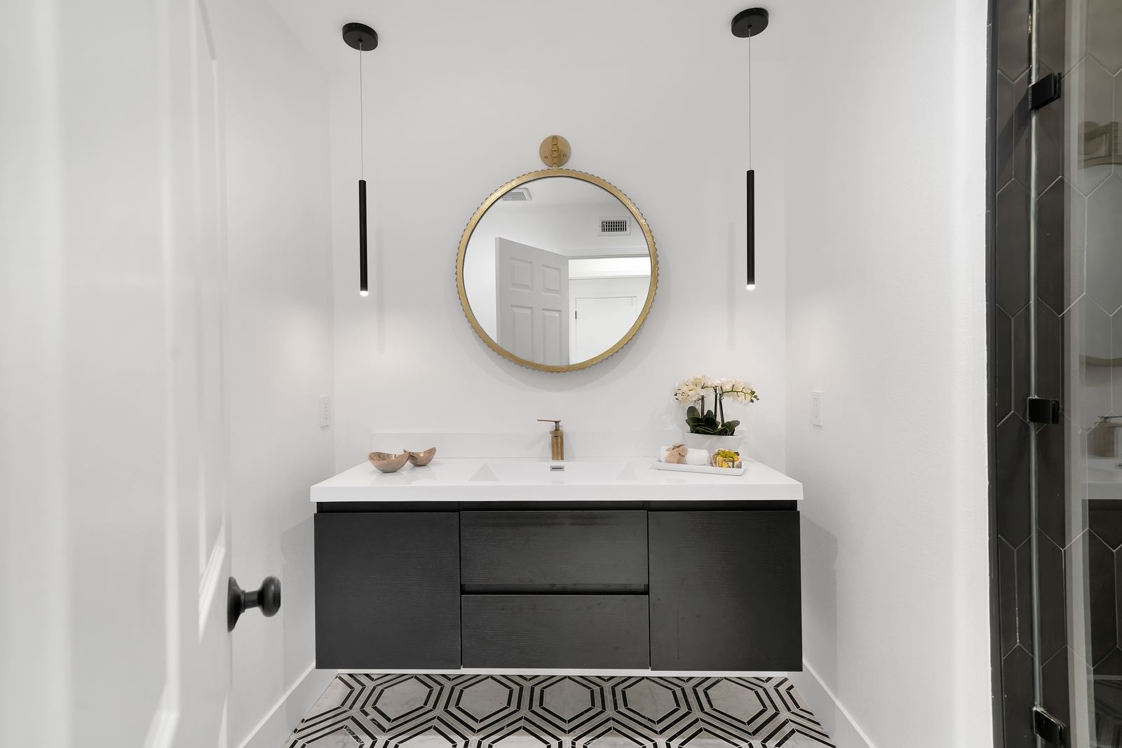 Bathroom remodel with floating black vanity, round brass mirror and marble hexagon mosaic floor