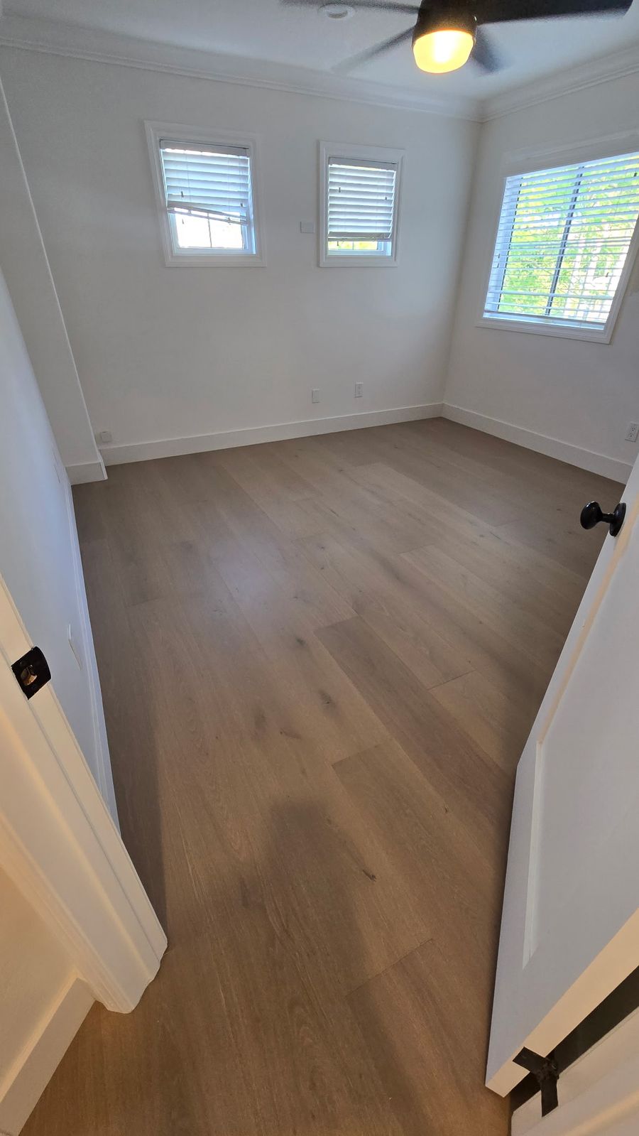 Engineered European oak hardwood floor in a Los Angeles bedroom with three windows