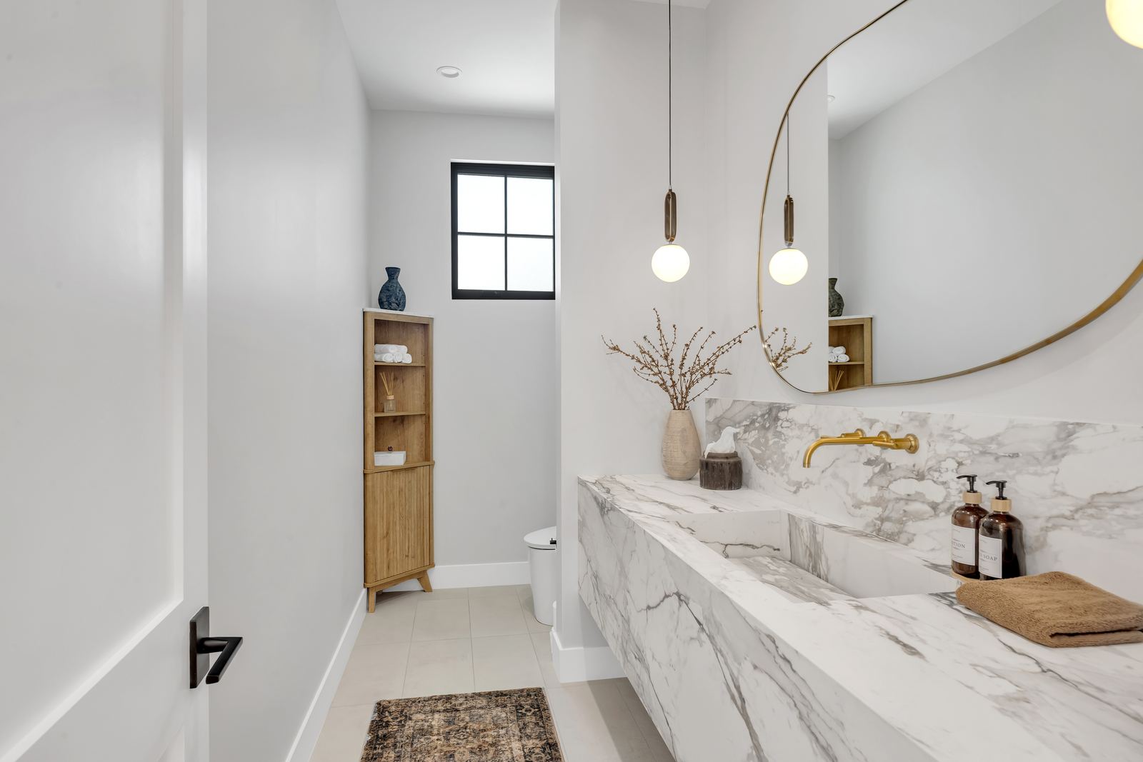 Powder room remodel with floating marble sink and brushed brass wall-mount faucet