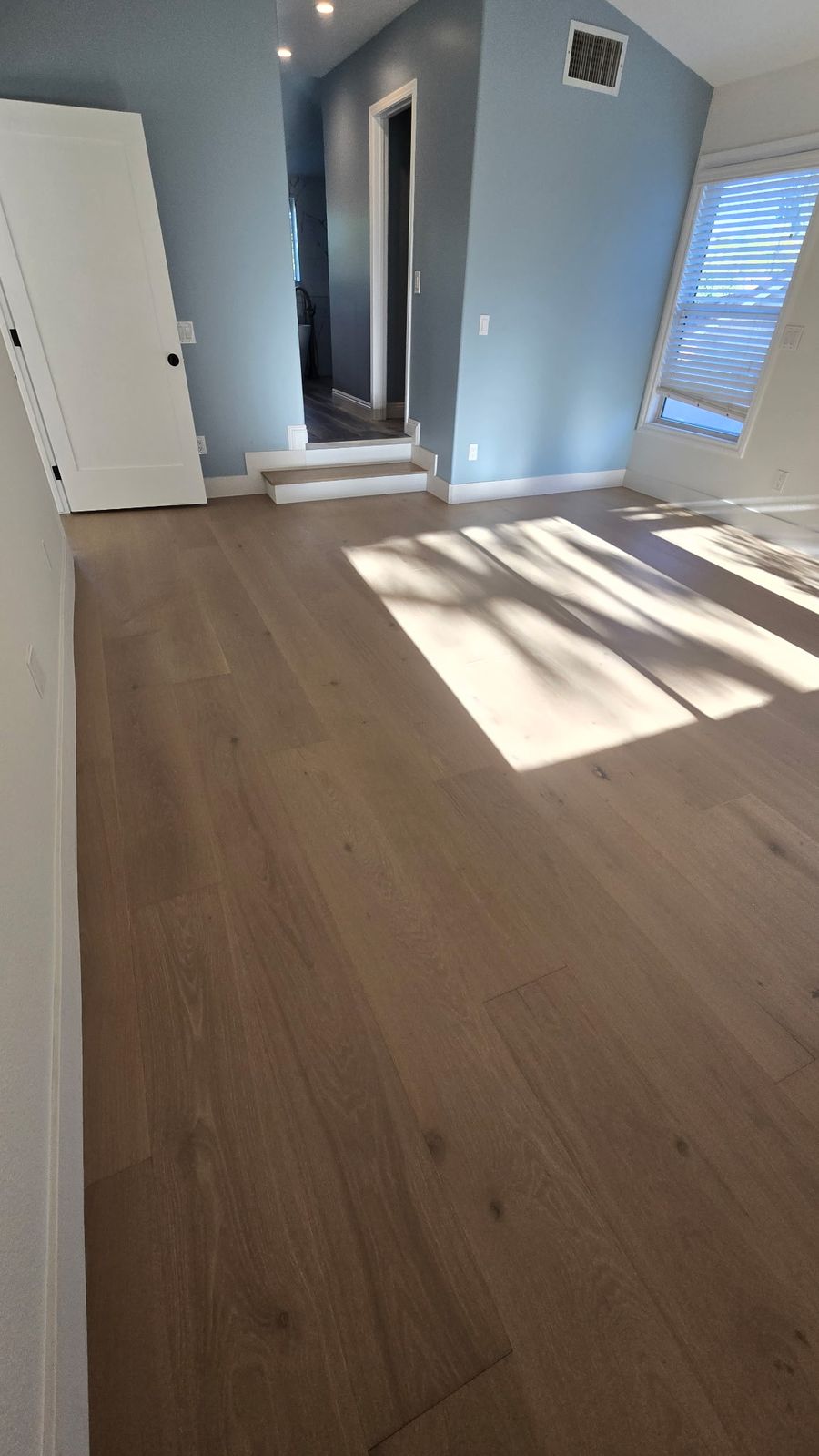 Primary bedroom with European oak flooring and a hardwood step to the bathroom