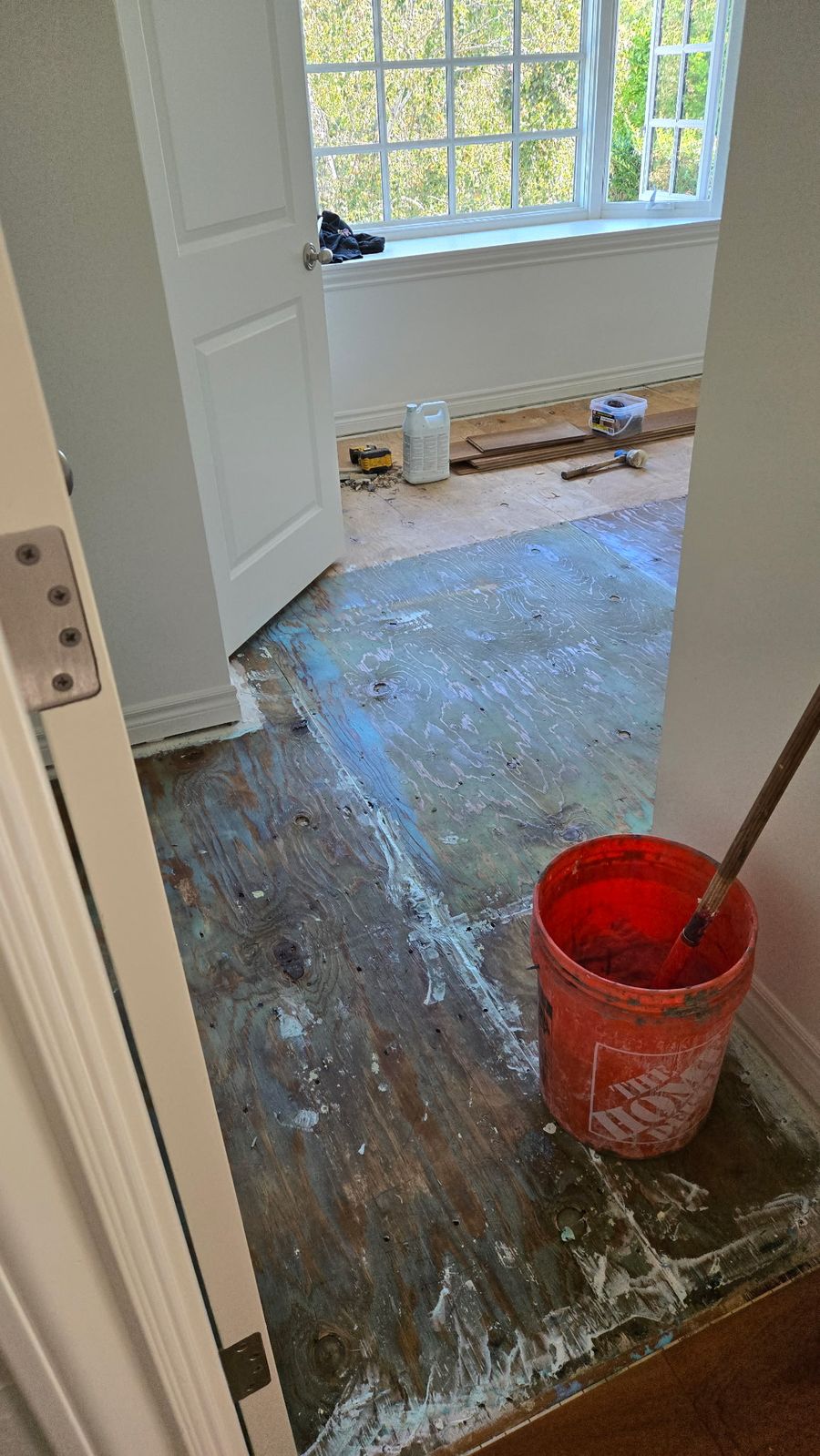 Plywood subfloor with old adhesive residue before floor preparation