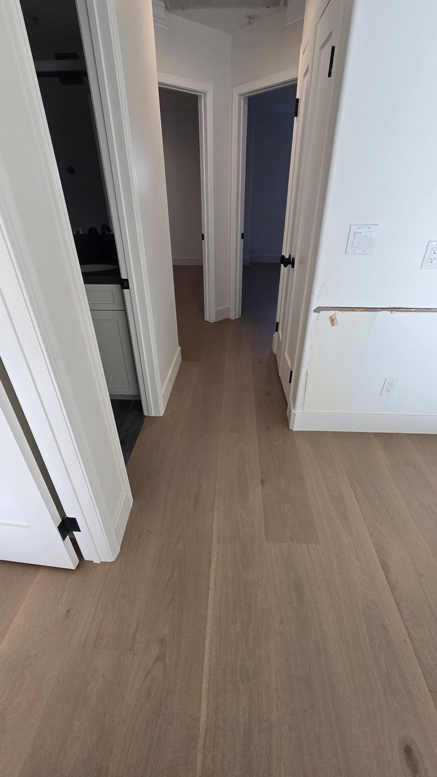 Wide-plank oak hardwood flooring in a Los Angeles hallway with bedroom doors