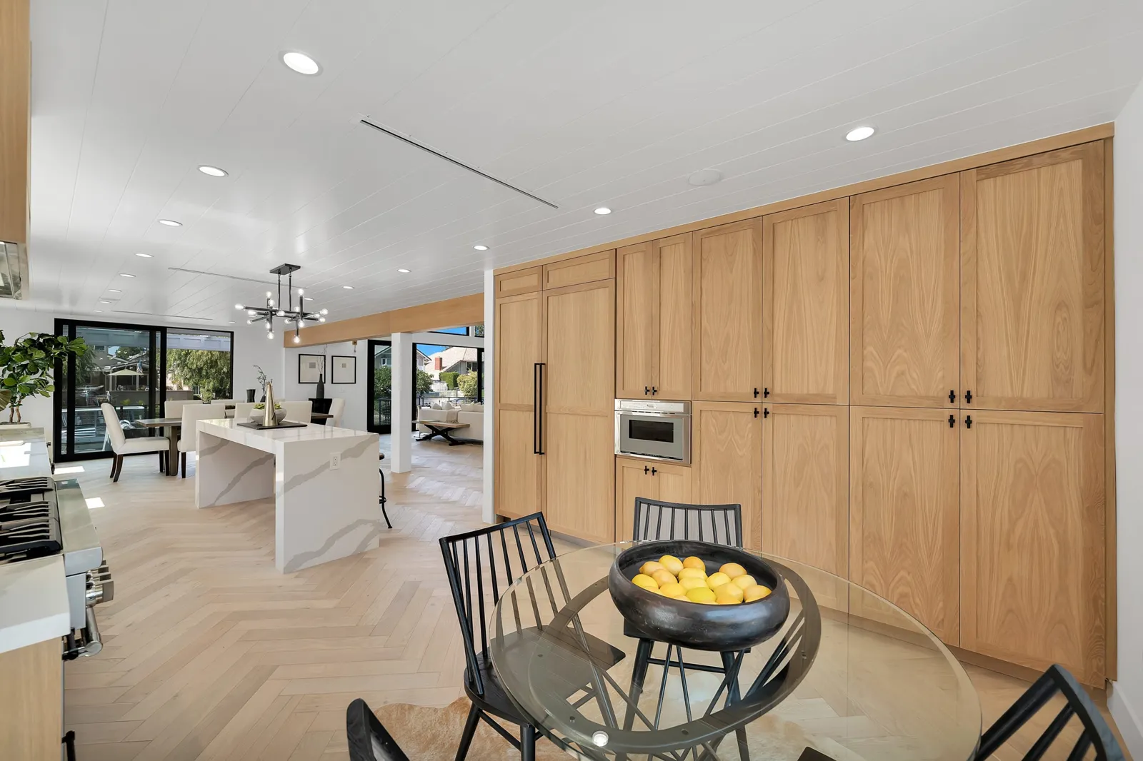 Light white oak herringbone flooring in an open kitchen and dining area