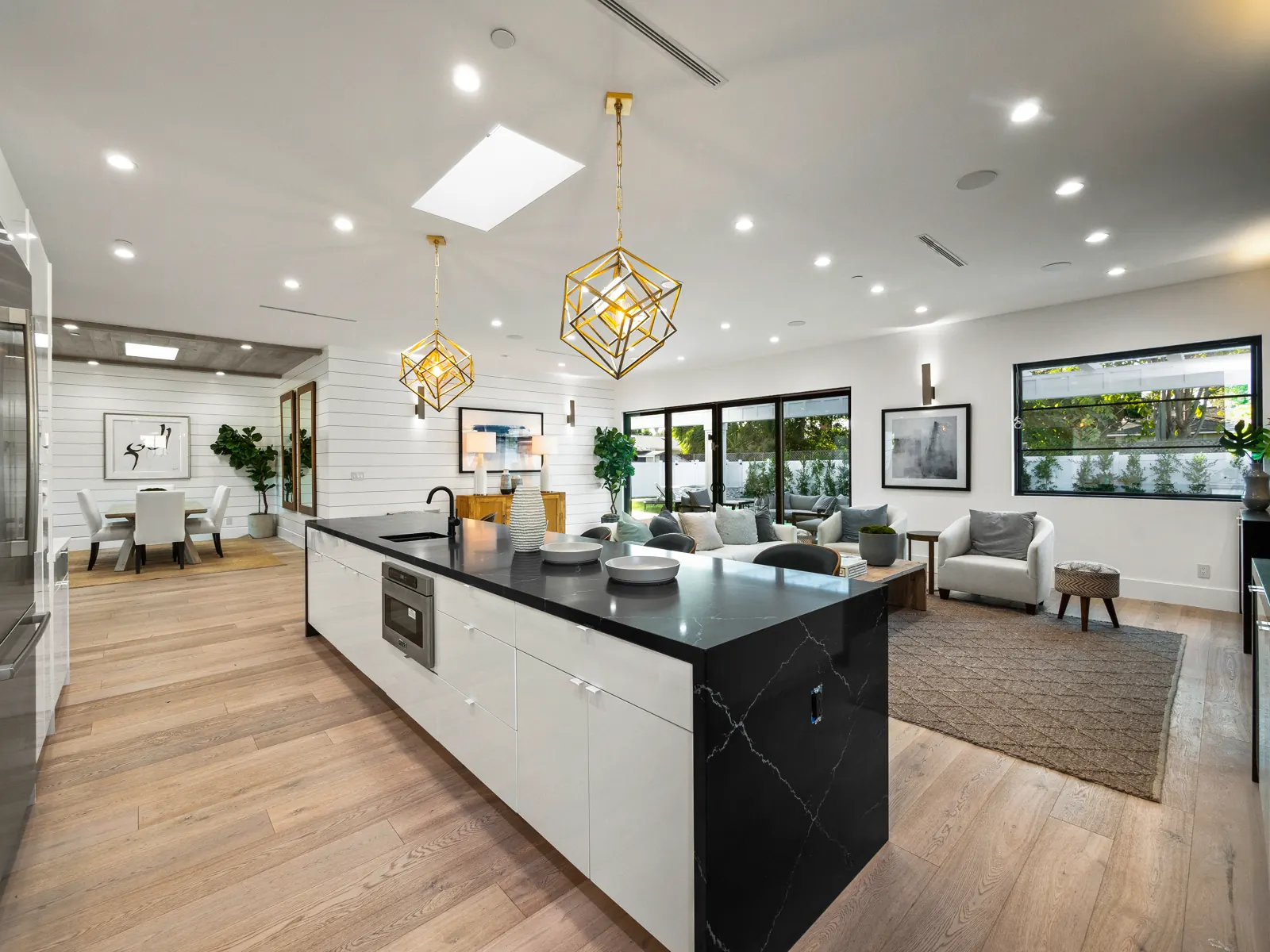 Kitchen with black island and light hardwood, Los Angeles, Glamour Flooring project